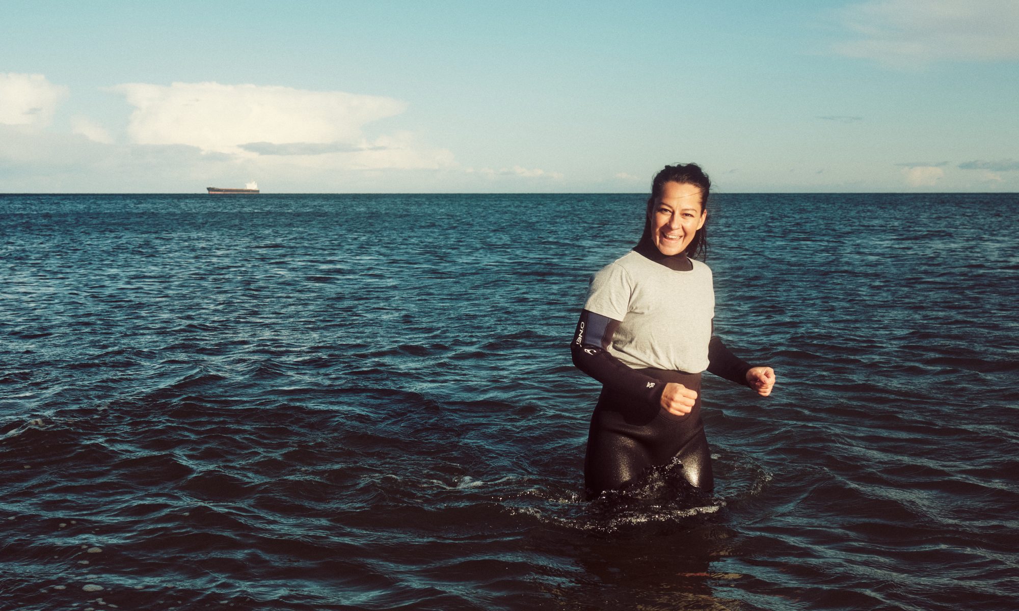 Nadia standing in the ocean smiling.