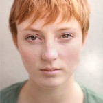 Headshot of Emma Holt outside, facing the camera. She has short hair, and is wearing a green top.