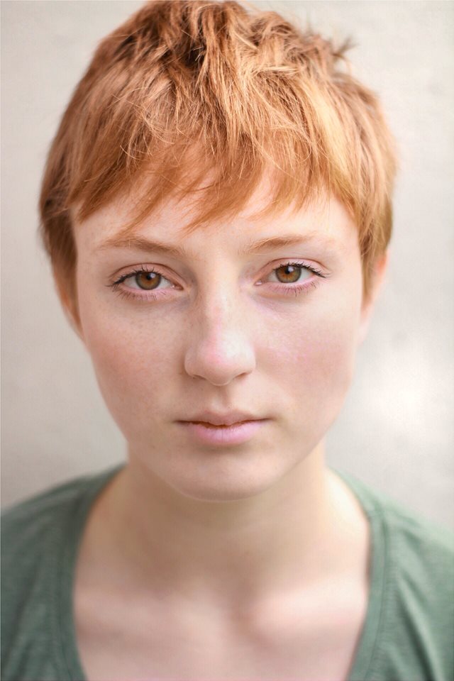 Headshot of Emma Holt outside, facing the camera. She has short hair, and is wearing a green top.