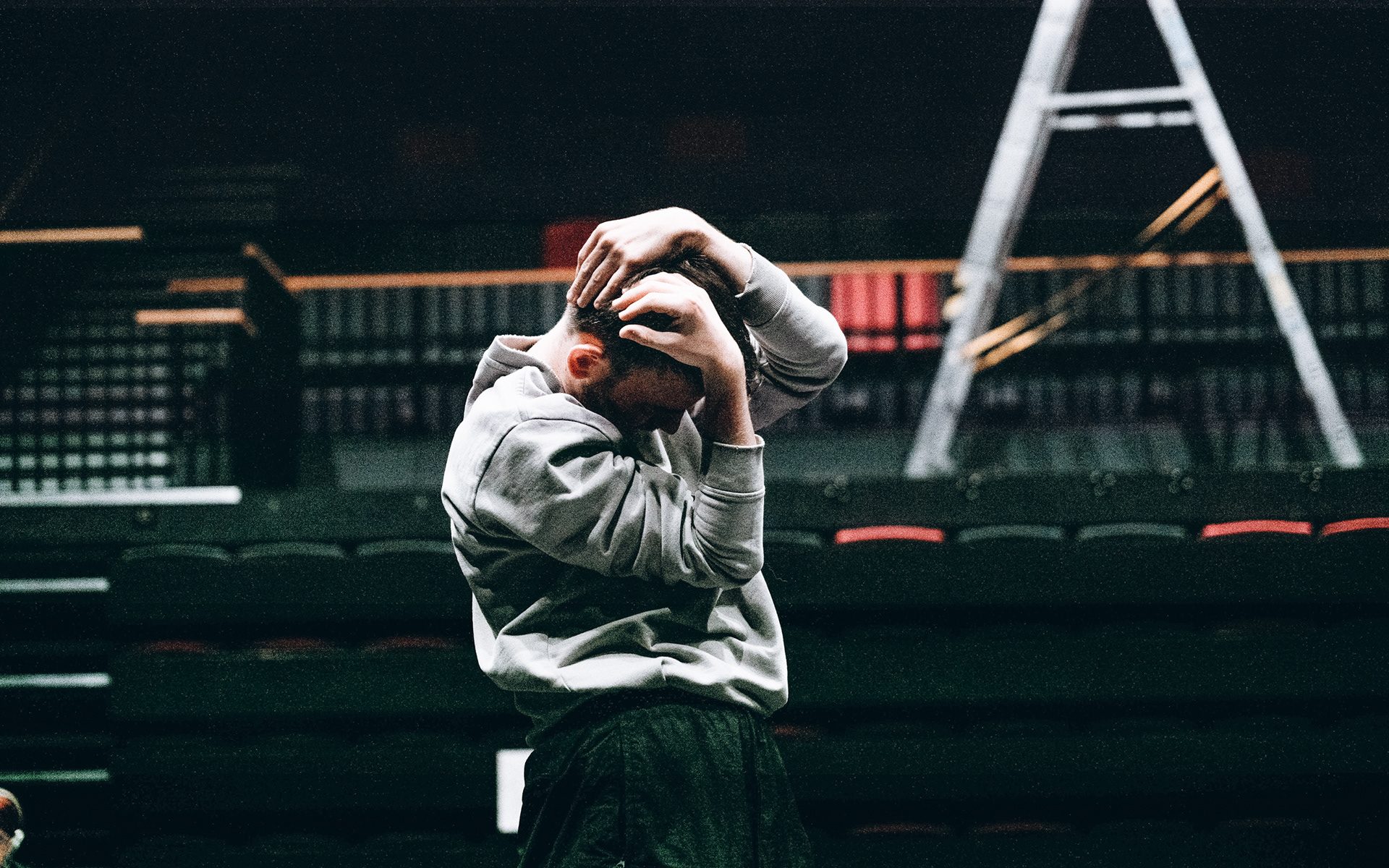 Anthony Lo-Giudice dancing in front of a stage. He is stood up, his head slightly forward, holding it in his hands.