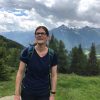 Louise smiling with trees and mountains in the background.