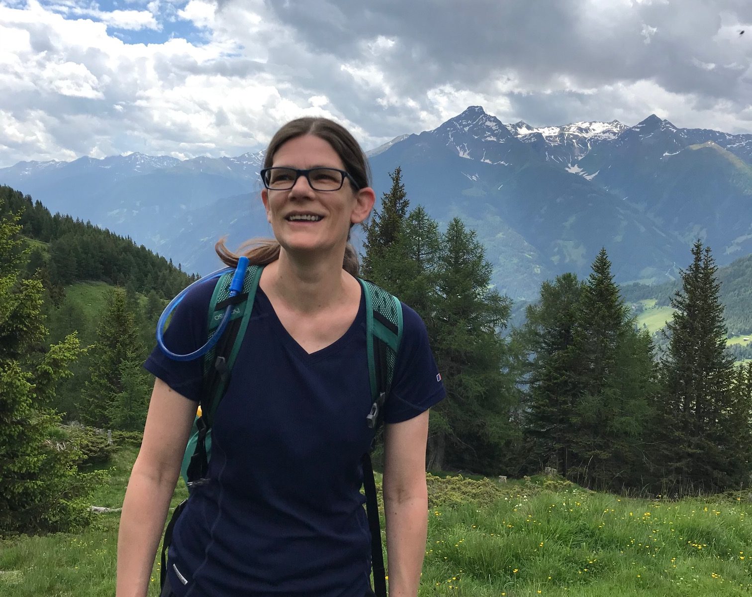 Louise smiling with trees and mountains in the background.
