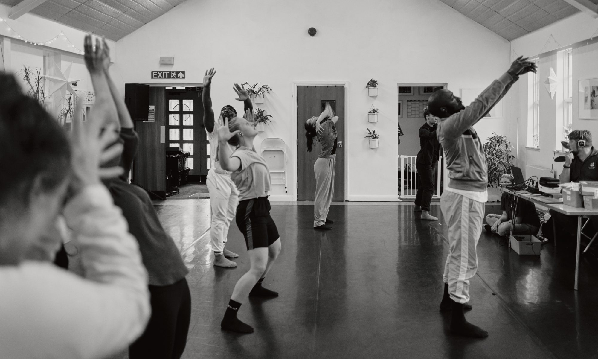 Five dancers in focus with their hands raised.